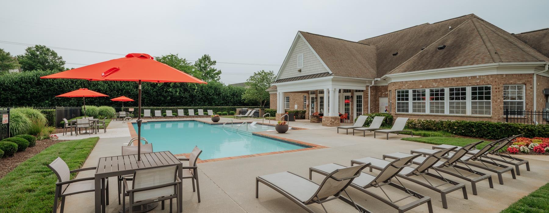 a swimming pool with chairs and umbrellas next to it
